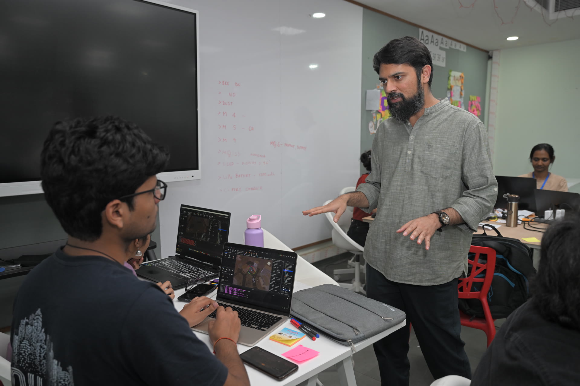 A mentor discussing a project with students during a game-dev session